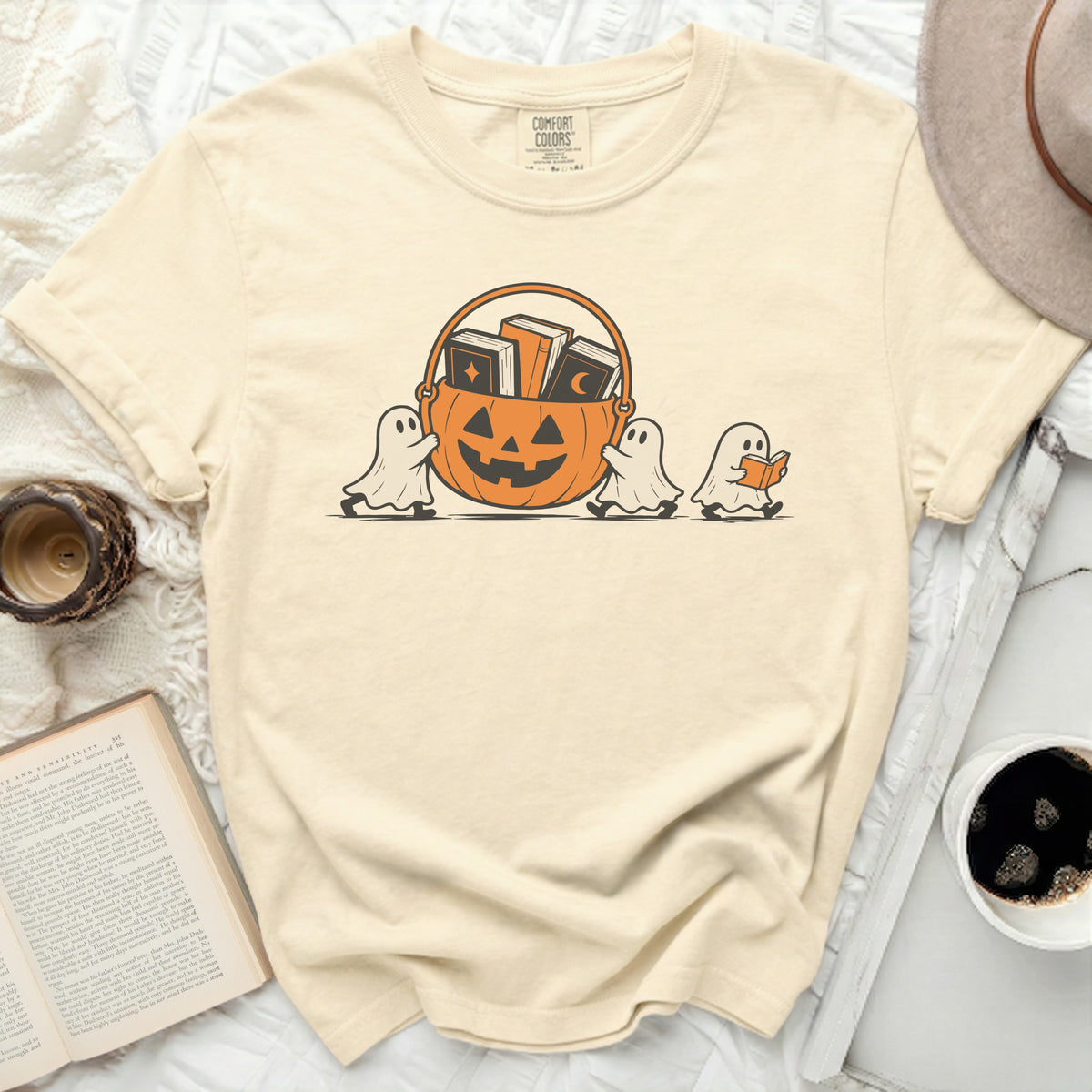 Cream t-shirt with cartoon ghosts carrying a pumpkin basket of books.