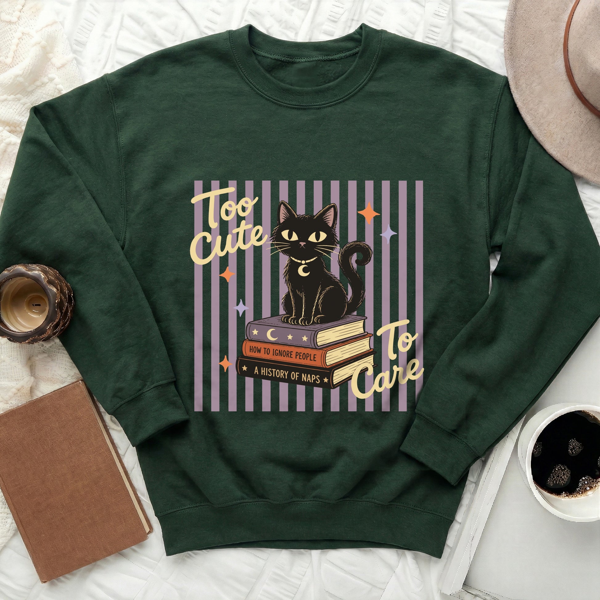 Green sweatshirt with a black cat on books graphic and text "Too Cute To Care".