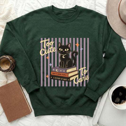 Green sweatshirt with a black cat on books graphic and text "Too Cute To Care".