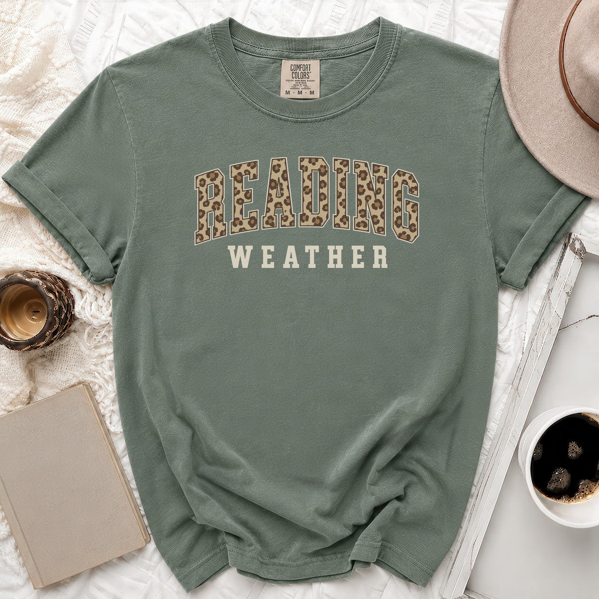 Sage green t-shirt with "READING WEATHER" in leopard print and cream letters.