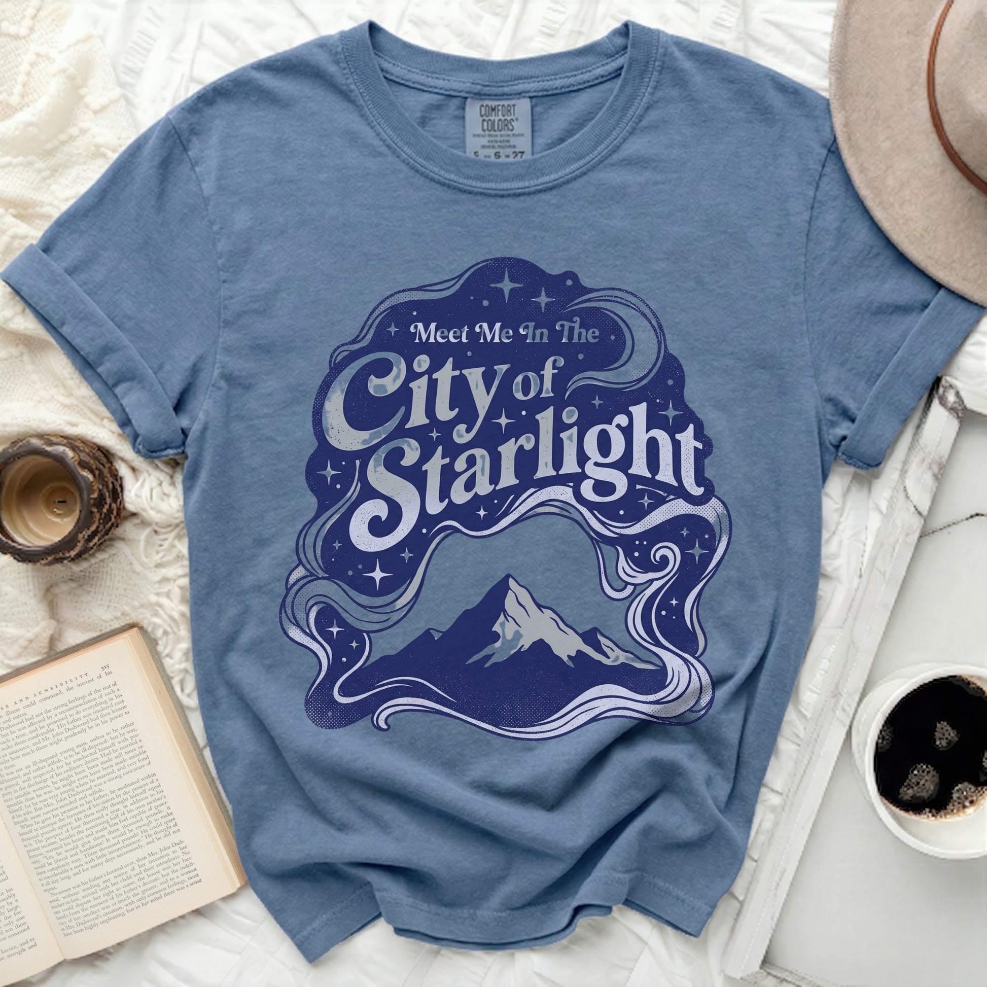 Blue t-shirt with "Meet Me In The City of Starlight" graphic.