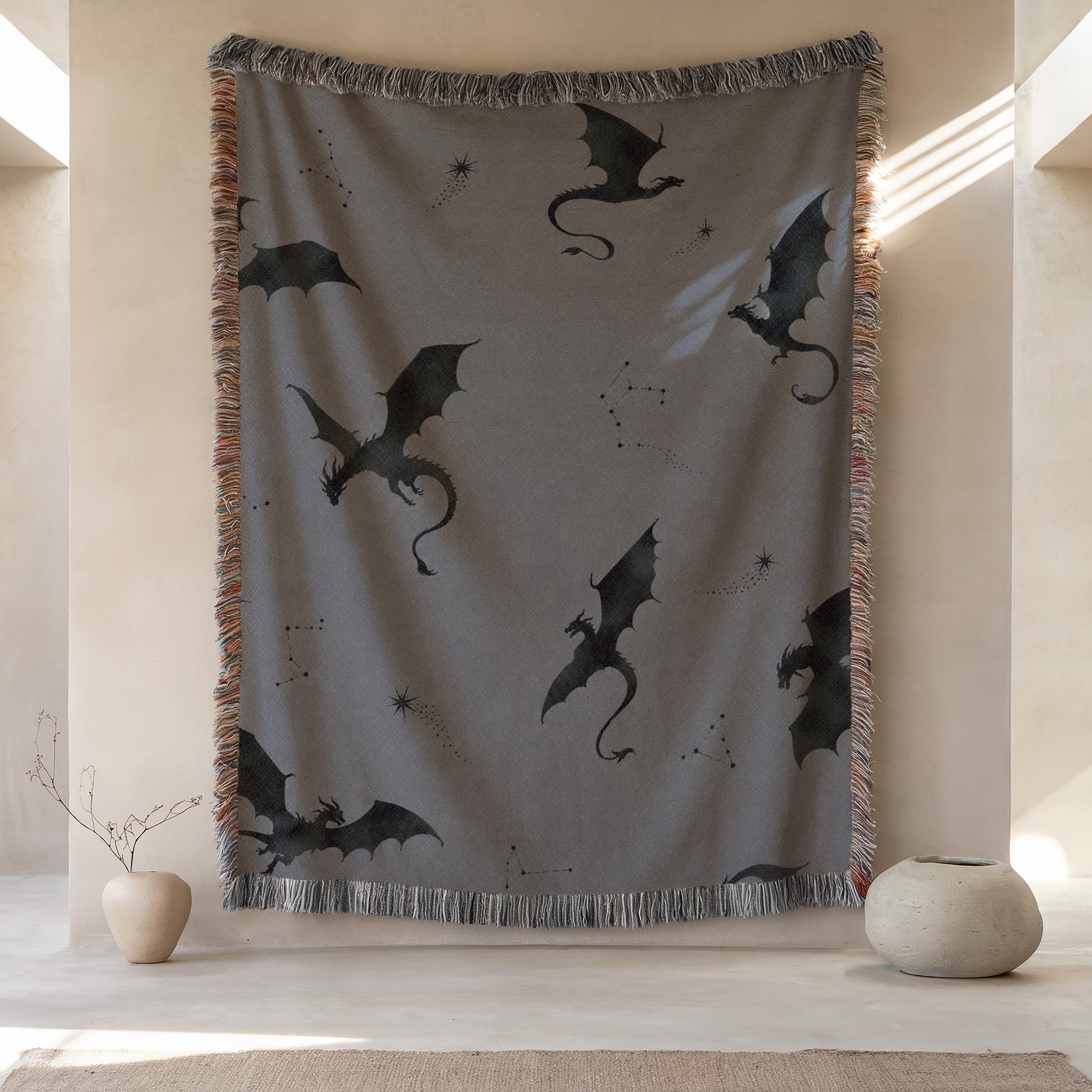 a large gray blanket with black dragon silhouettes on it, hanging on a wall. There are two small vases placed next to the blanket, one on the left and one on the right.