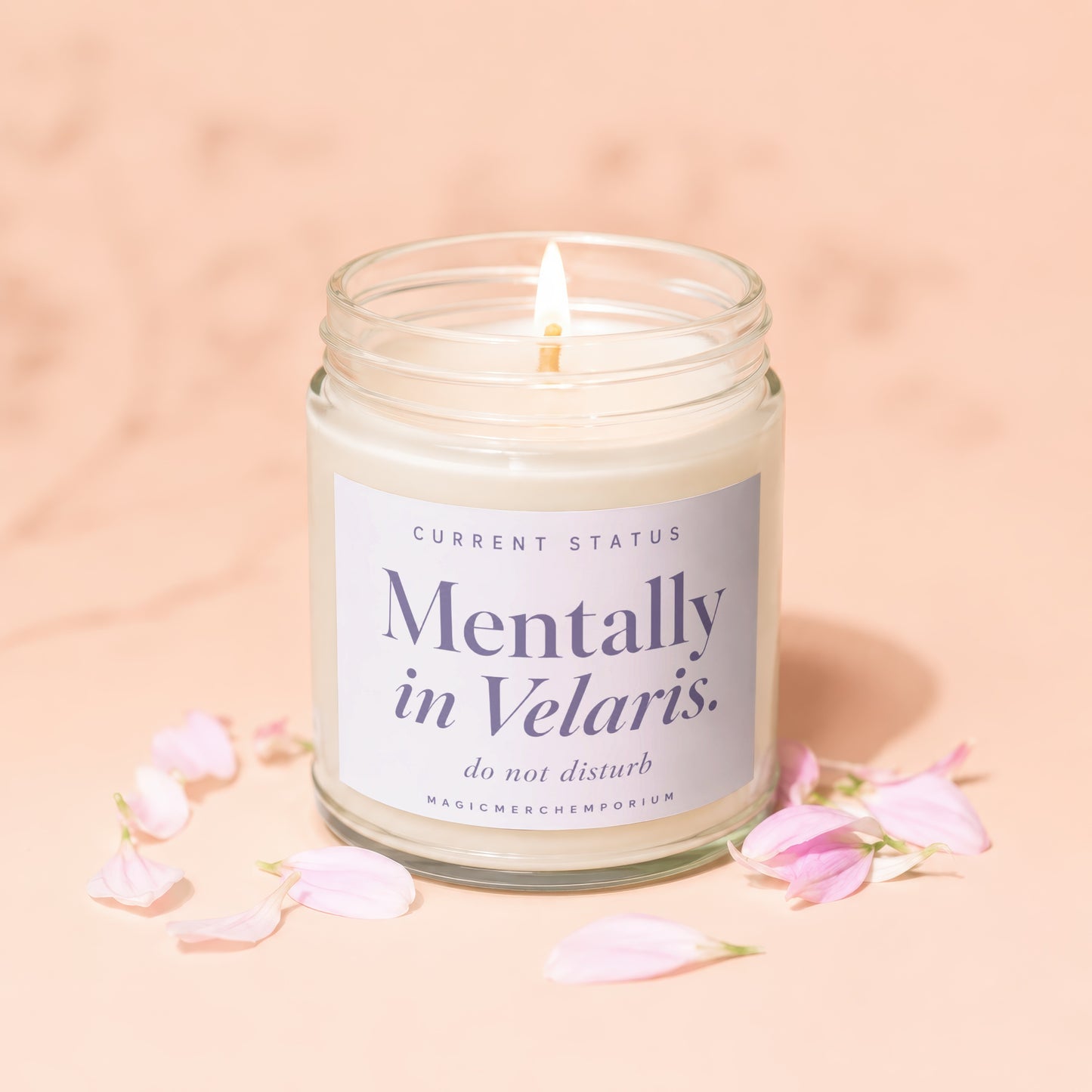 Candle with "Mentally in Velaris" text, lit and surrounded by pink petals.