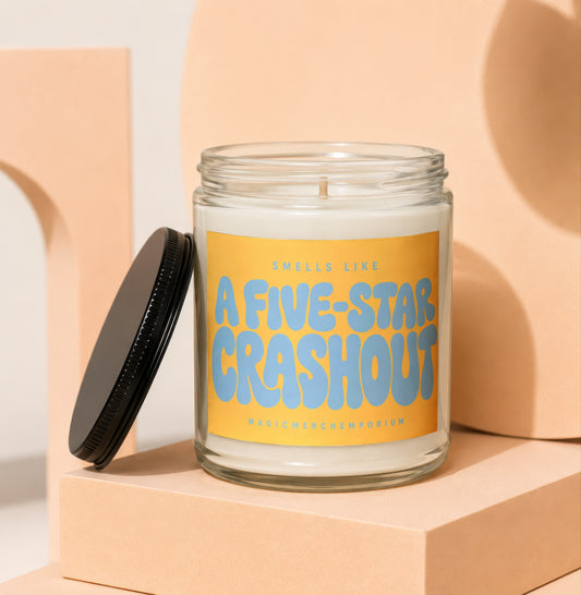 Jar candle with orange label reading "SMELLS LIKE A FIVE-STAR CRASHOUT".
