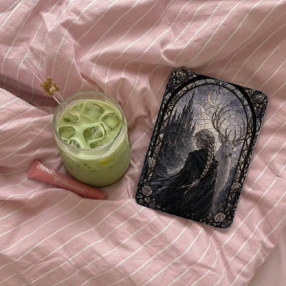 Glass of matcha with ice, a lip balm, and a phone case on pink striped sheets.