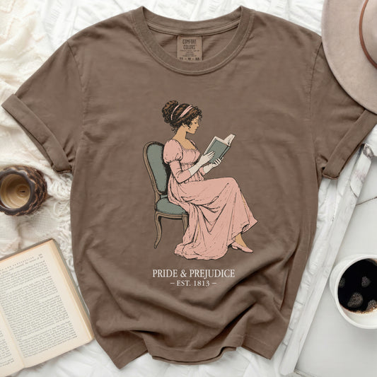 Brown t-shirt with illustration of Jane Austen reading, "Pride & Prejudice Est. 1813"