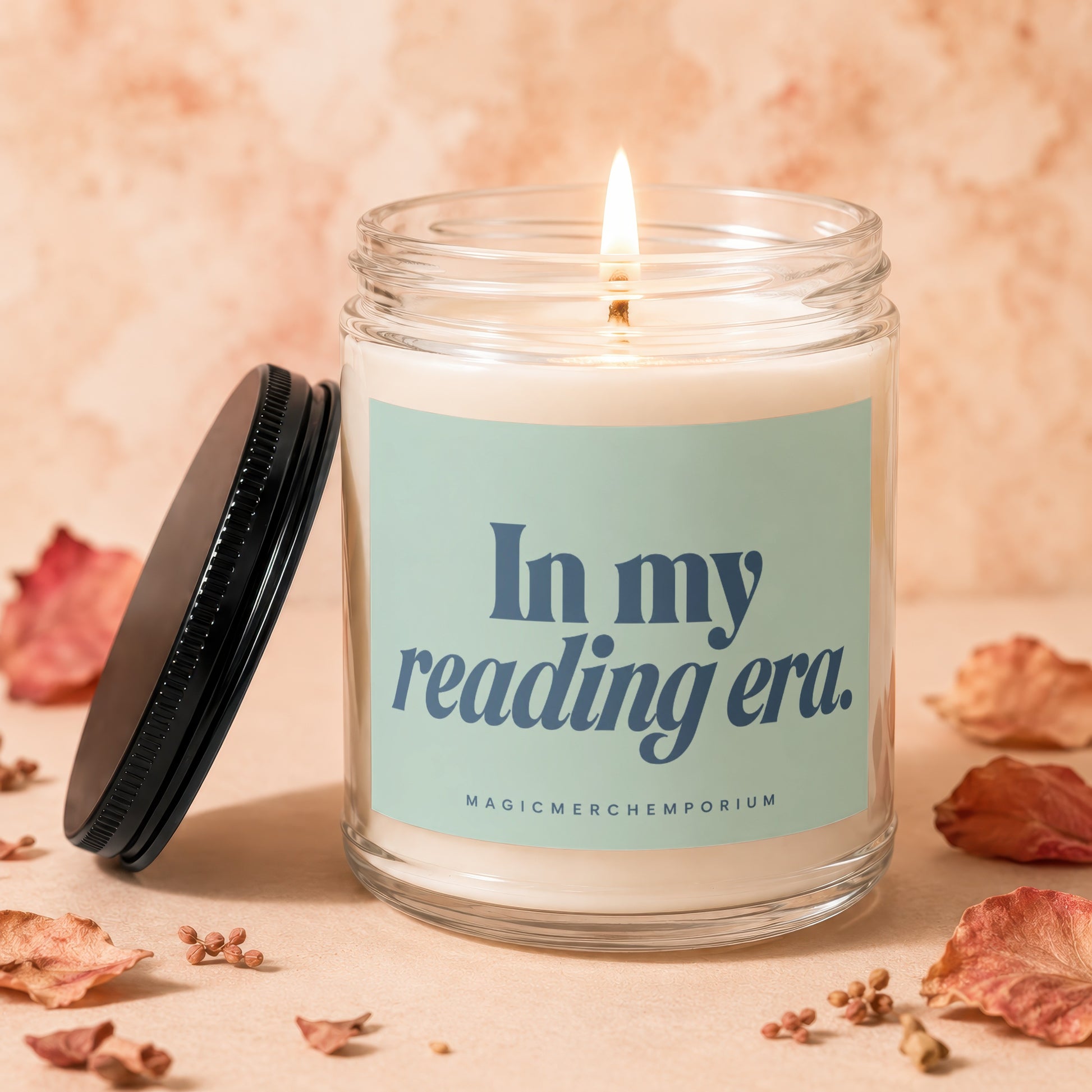 Candle with "In my reading era." text on label, lit flame, and lid nearby.
