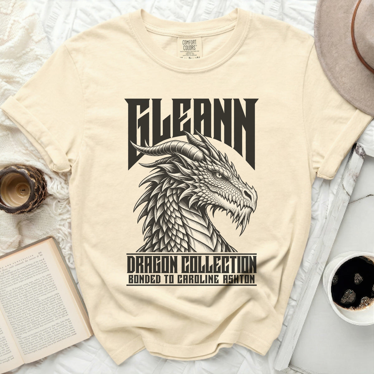 Cream t-shirt with black graphic of a dragon head and text "FLEANN DRAGON COLLECTION BONDED TO CAROLINE ASHTON".