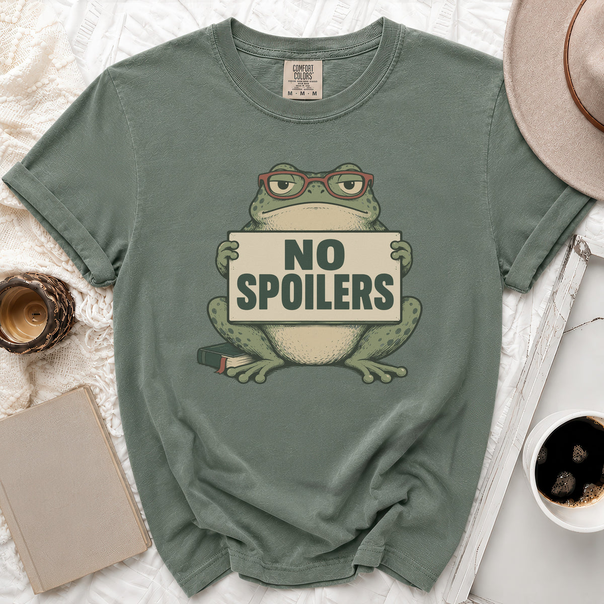 Green t-shirt with a cartoon frog wearing glasses holding a "NO SPOILERS" sign.