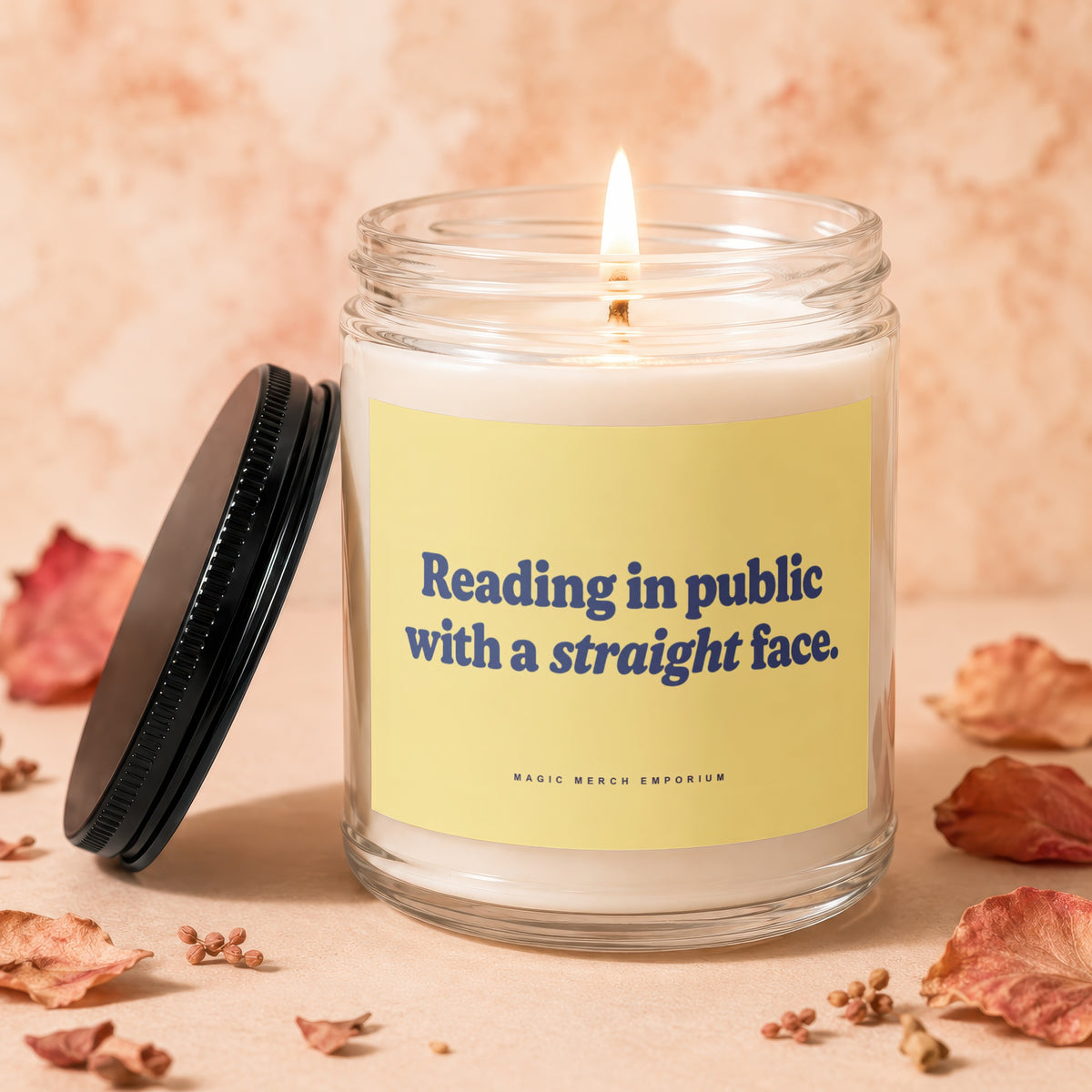 Burning glass candle with yellow label that reads "Reading in public with a straight face."