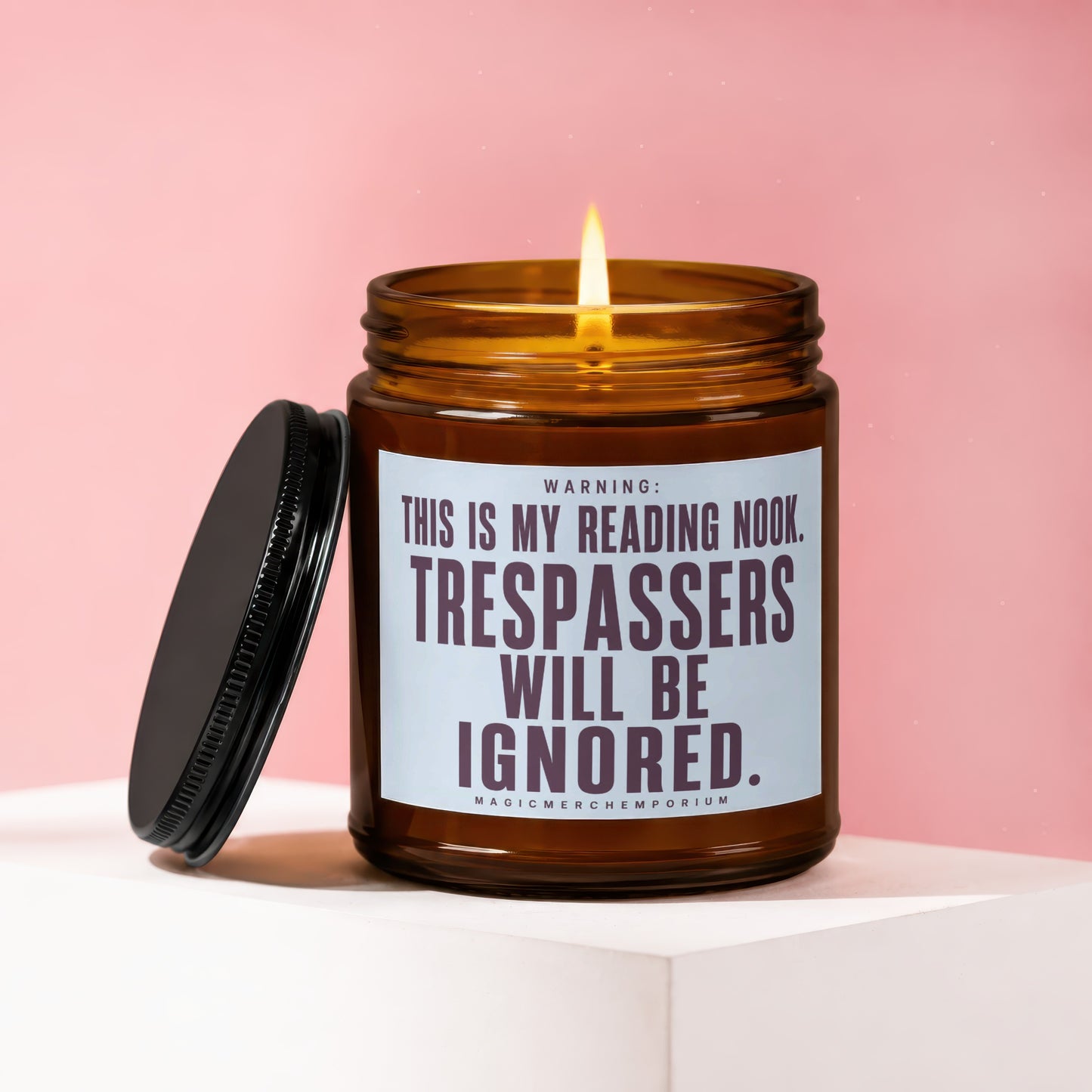 Amber jar candle with lit wick, "This is my reading nook. Trespassers will be ignored." text.