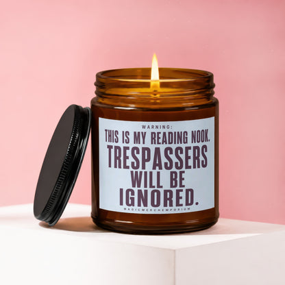 Amber jar candle with lit wick, "This is my reading nook. Trespassers will be ignored." text.