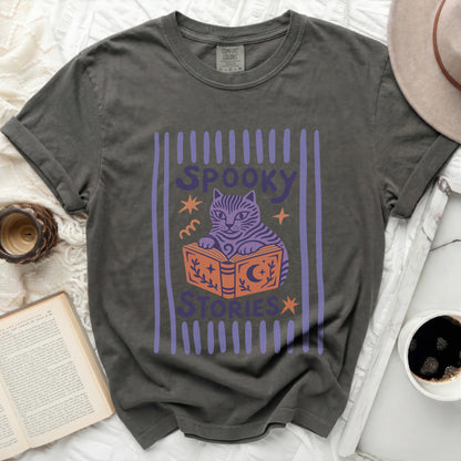 Grey t-shirt with a purple graphic of a cat reading a book and text "SPOOKY STORIES".