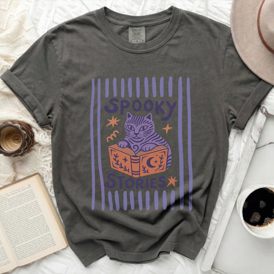 Grey t-shirt with a purple graphic of a cat reading a book and text "SPOOKY STORIES".