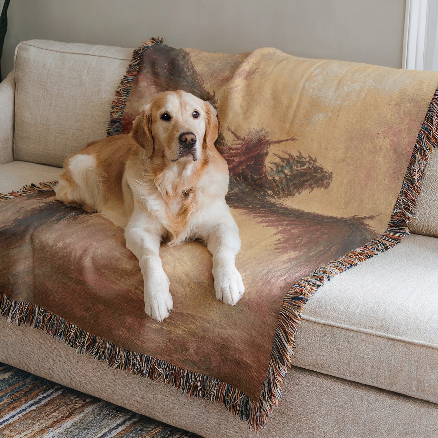 A golden retriever dog is lying on a beige couch, with a colorful blanket featuring a landscape design.