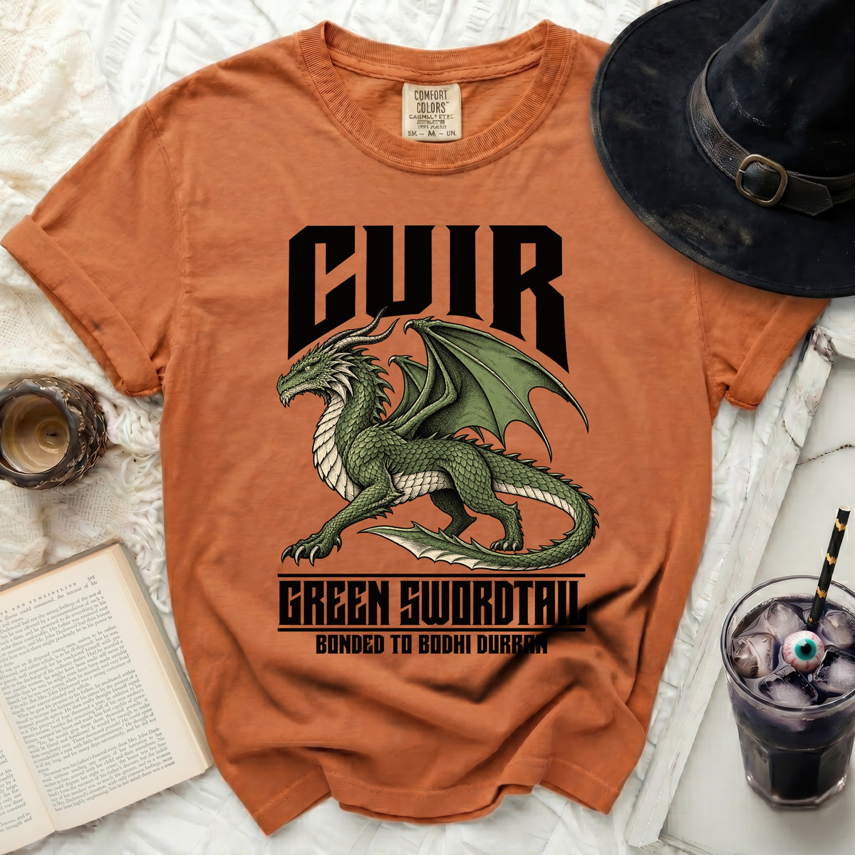 Orange Comfort Colors t-shirt with a green dragon graphic and text: CUIR, GREEN SWORDTAIL, BONDED TO BODHI DURRAN.