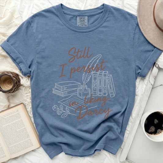 Blue t-shirt with "Still I persist in liking Darcy" text and line art illustration.