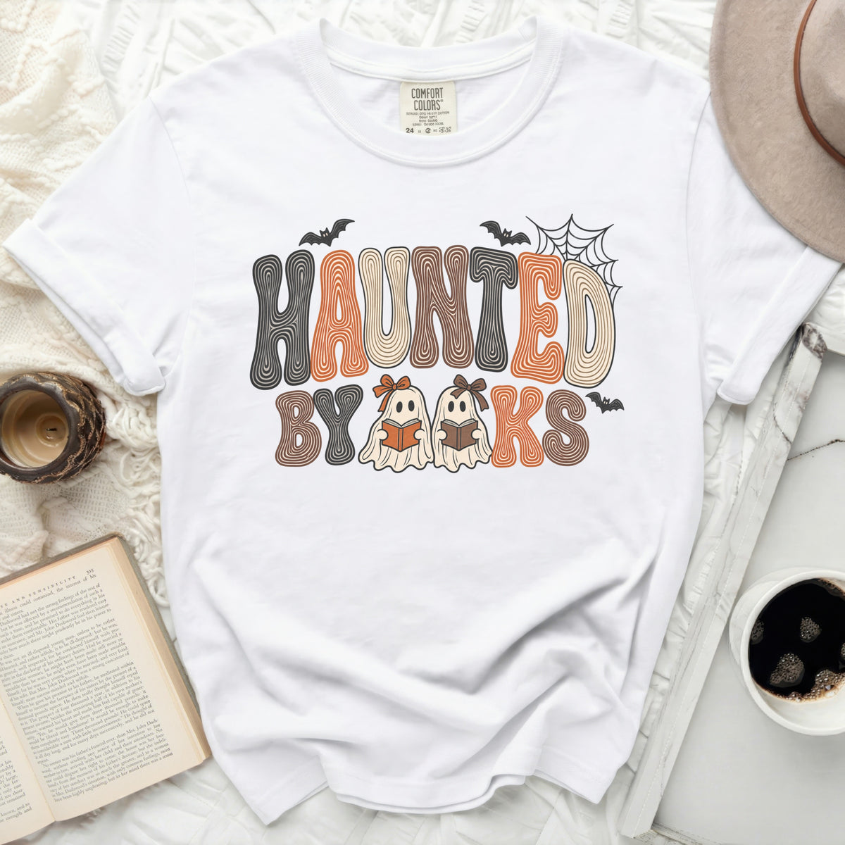 White t-shirt with "Haunted By Books" graphic featuring ghosts reading books.