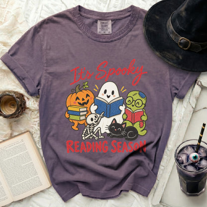 Purple t-shirt with "It's Spooky Reading Season" featuring Halloween characters reading books.