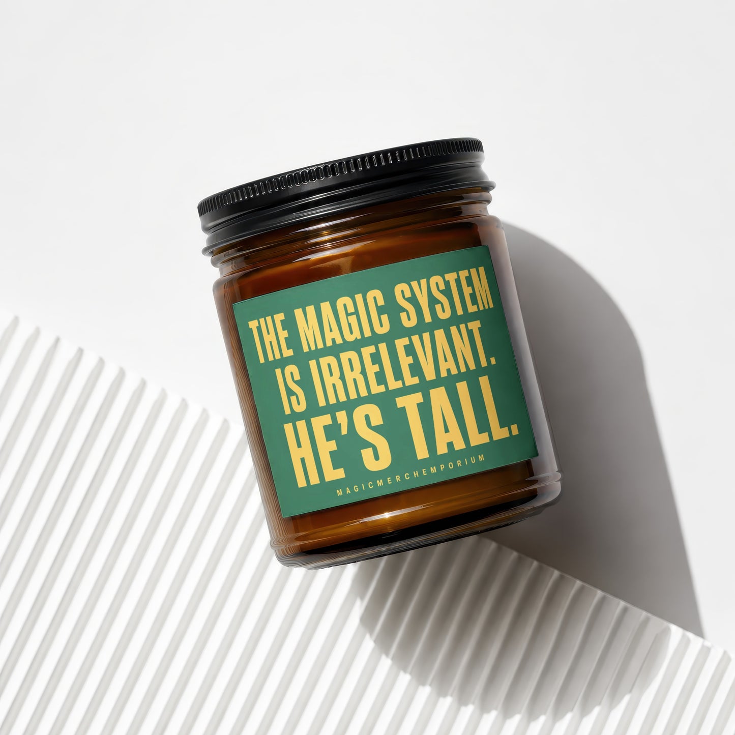 Amber candle with green label quoting "THE MAGIC SYSTEM IS IRRELEVANT. HE'S TALL."