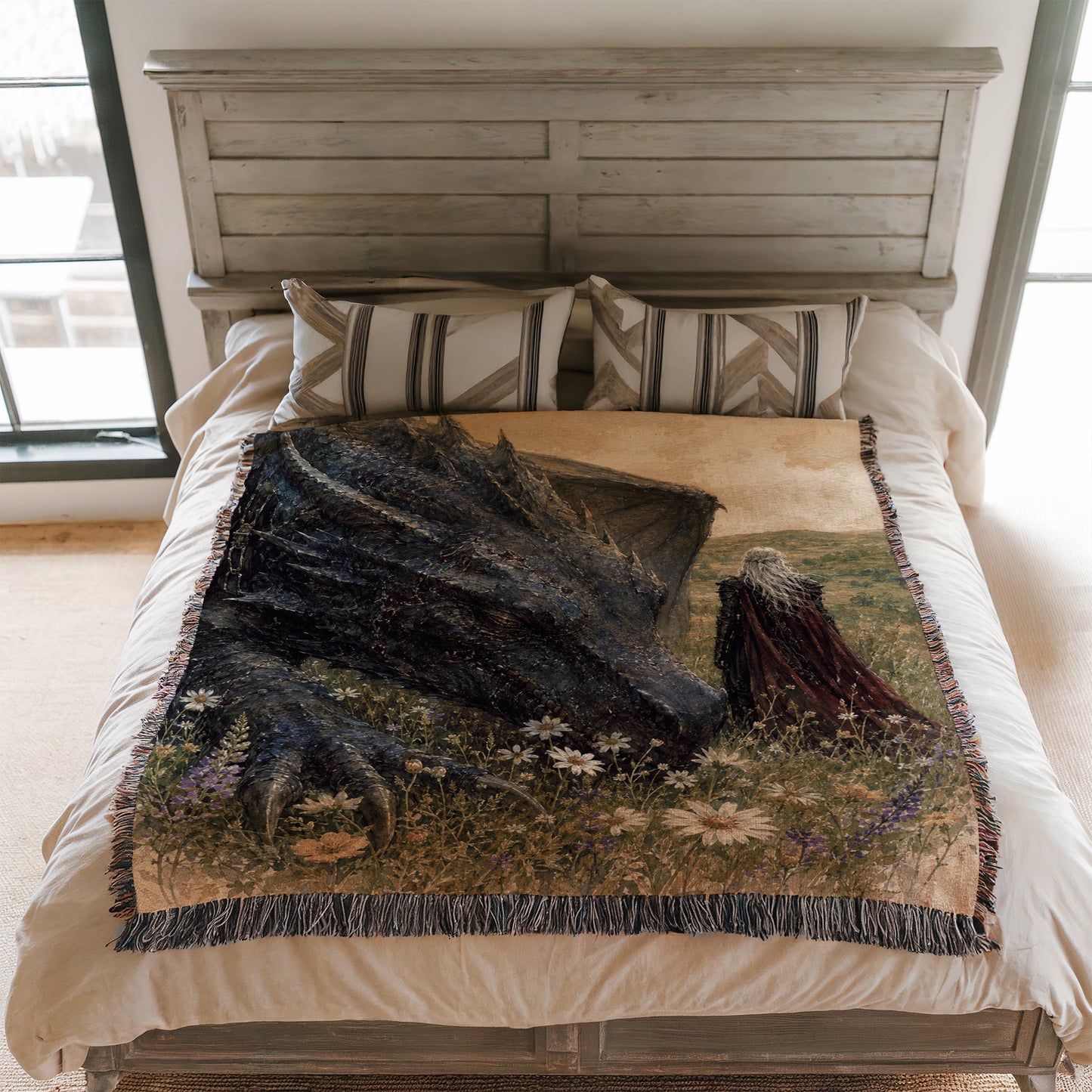 a bed with a large, detailed dragon-themed blanket on it. The dragon appears to be a black creature with a long neck and sharp teeth, set against a grassy field with flowers. The bed is framed by a wooden headboard, and there are two pillows on the bed.