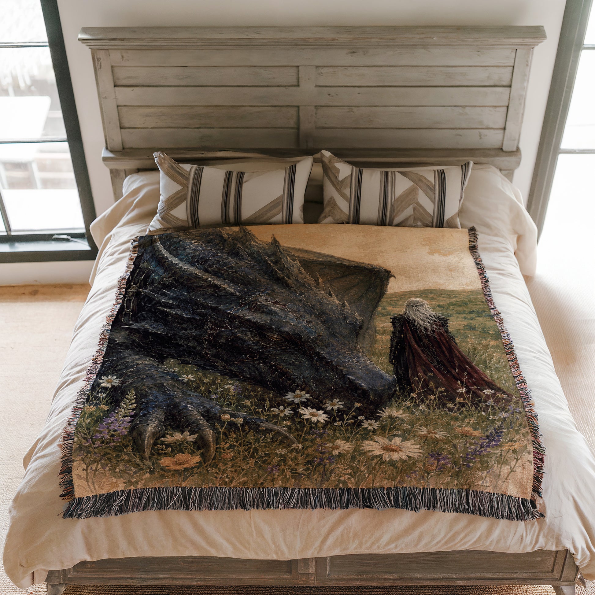 a bed with a large, detailed dragon-themed blanket on it. The dragon appears to be a black creature with a long neck and sharp teeth, set against a grassy field with flowers. The bed is framed by a wooden headboard, and there are two pillows on the bed.