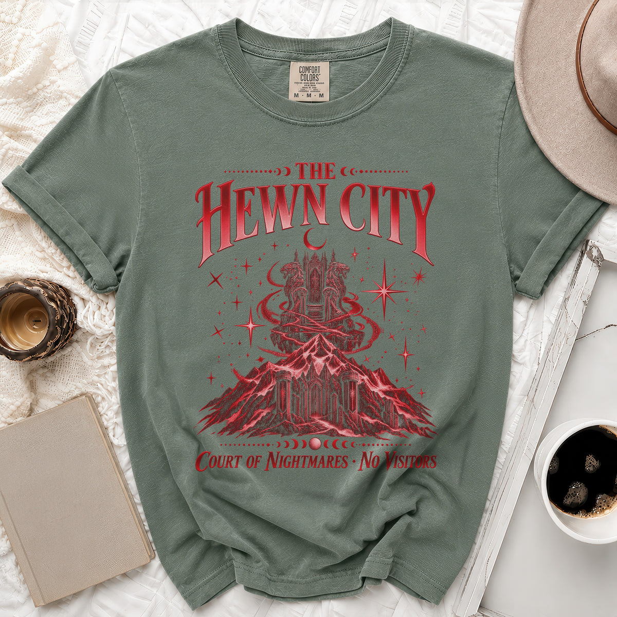 Green t-shirt with red graphic of a mountain city and text "The Hewn City Court of Nightmares No Visitors".