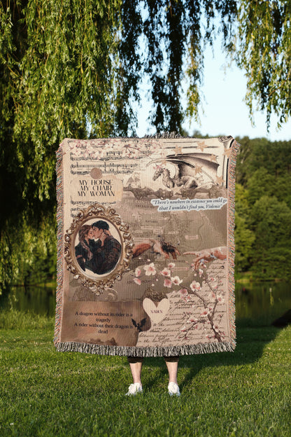 A person is standing in a grassy area, holding a large blanket that features a collage of various images, including a dragon, a couple embracing, and text.