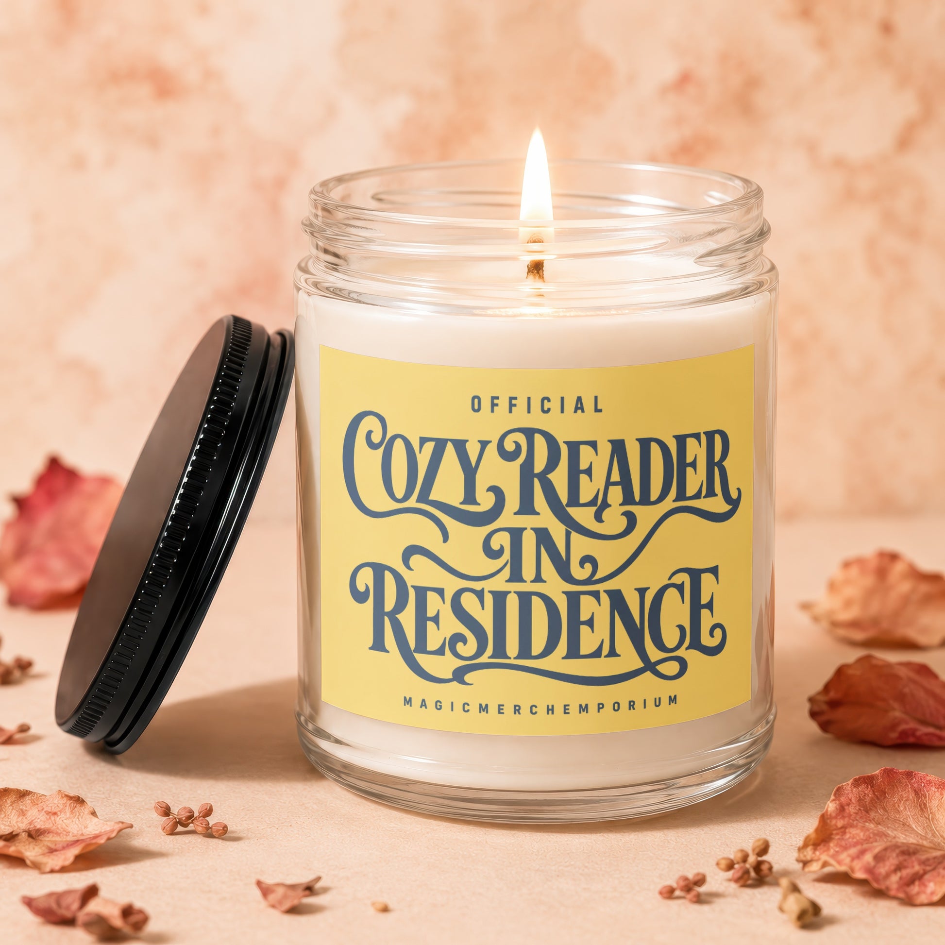 Candle with "Cozy Reader In Residence" text on yellow label.