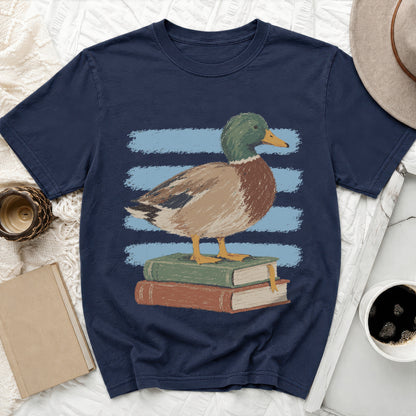 Mallard duck standing on stacked books with blue stripes on dark t-shirt.