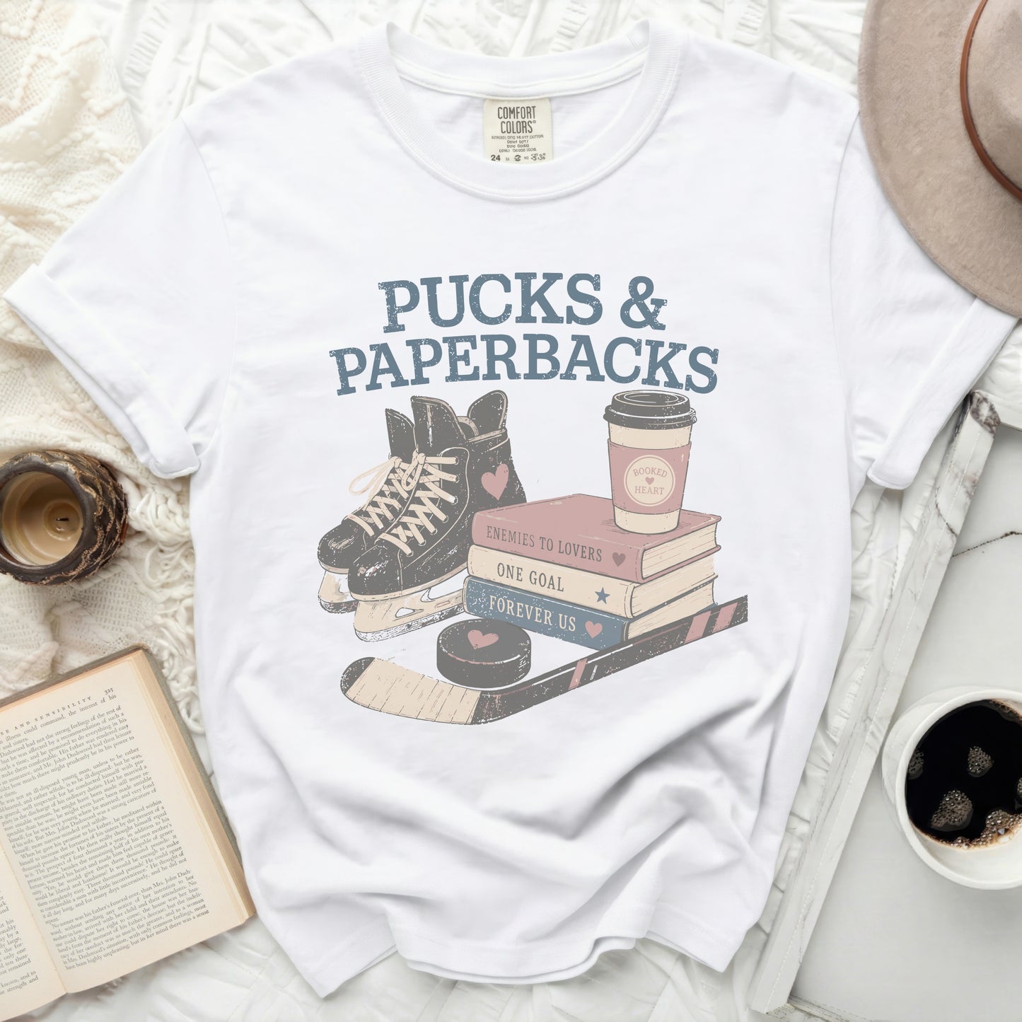 White t-shirt with "Pucks & Paperbacks" and hockey graphic.
