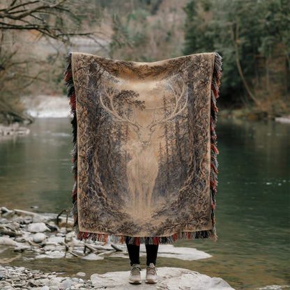 A person stands in front of a river, holding a large rug with a deer design on it.