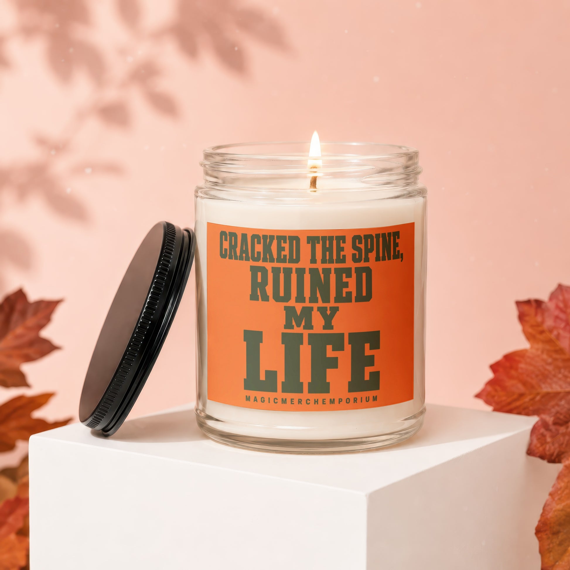 Candle with orange label reading "CRACKED THE SPINE, RUINED MY LIFE".
