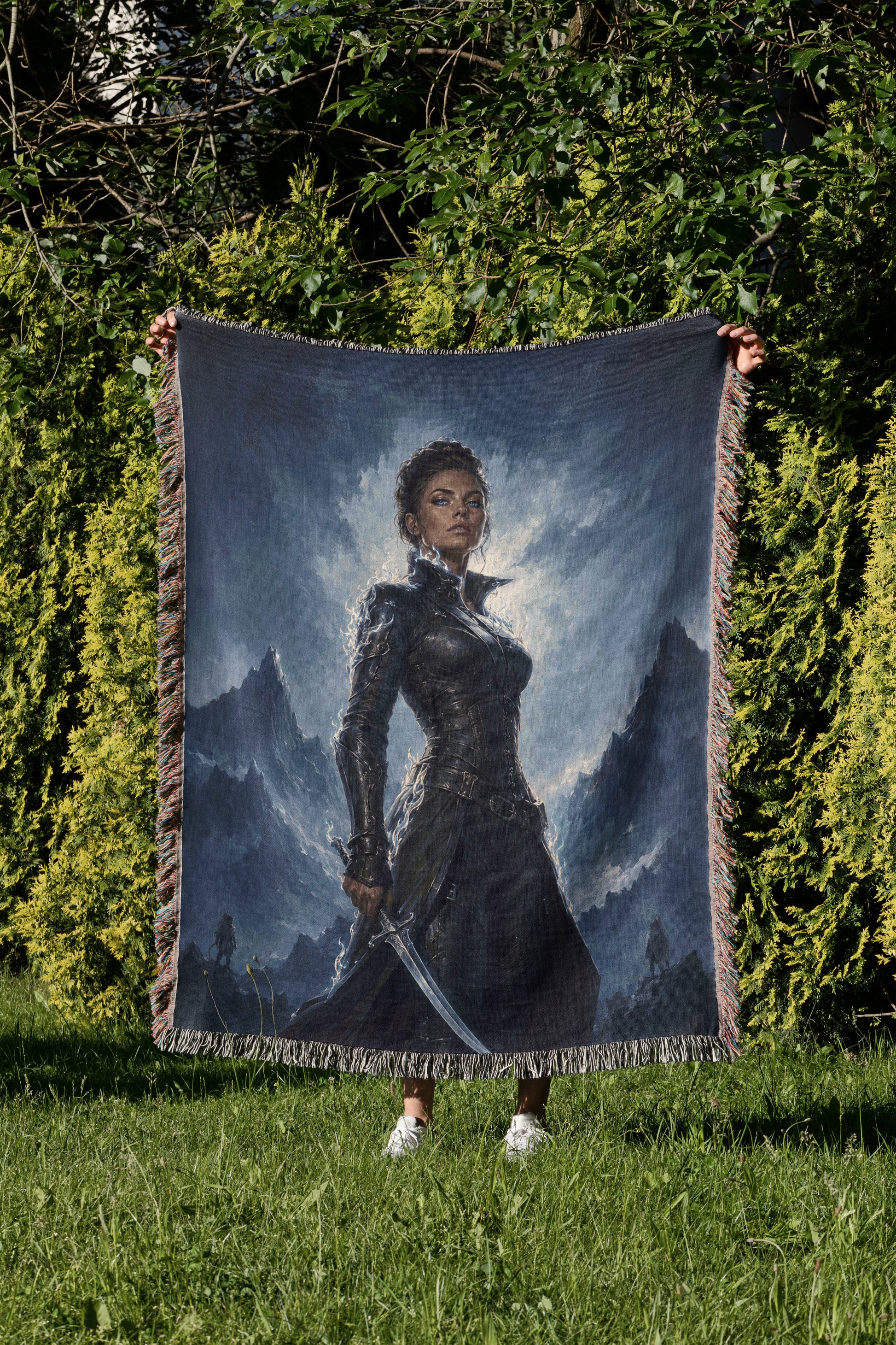 A person is holding up a large tapestry or blanket featuring a painting of a woman in a dark outfit, standing in a grassy field with mountains in the background.