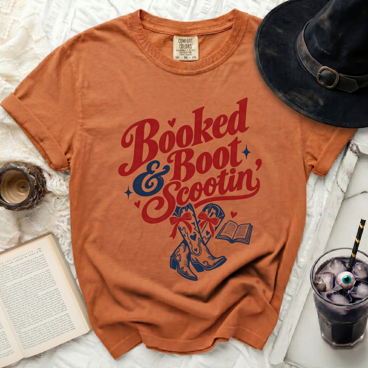 Orange t-shirt with "Booked & Boot Scootin" graphic featuring boots and a book.