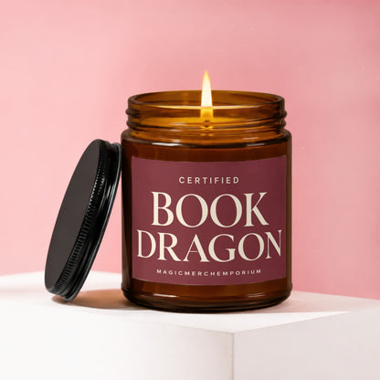 Amber glass candle labeled "Certified Book Dragon" with the lid off.