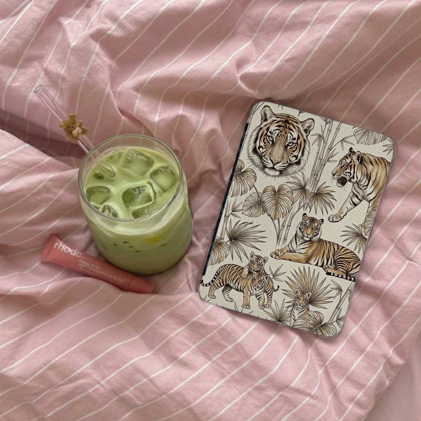 A phone case with a tiger print pattern next to a matcha drink and lip balm.