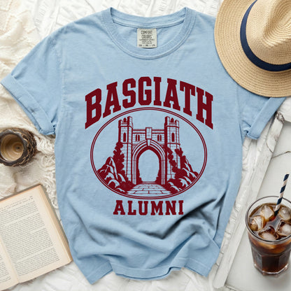 Light blue crewneck t-shirt featuring a maroon Basgiath Alumni castle graphic, surrounded by a straw hat, iced drink, and book.