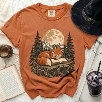 Orange t-shirt with a graphic of a fox reading a book under the moon.