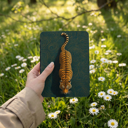 Hand holding a notebook with a tiger design, set outdoors in a field of daisies.