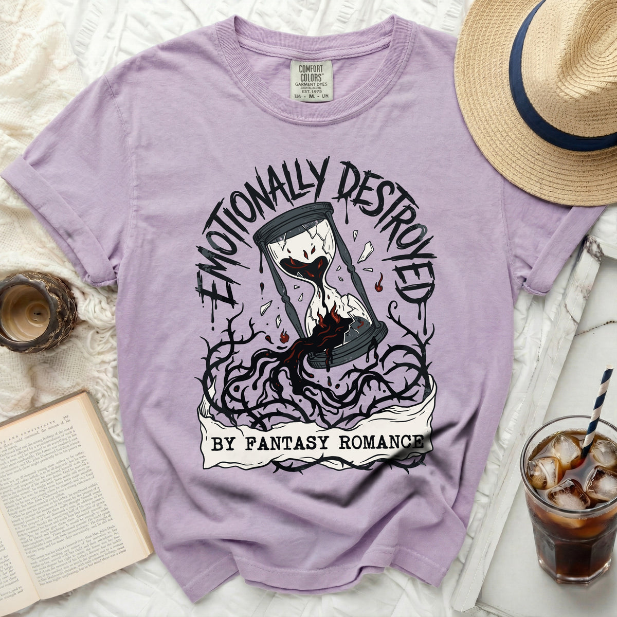 Purple t-shirt with "Emotionally Destroyed by Fantasy Romance" hourglass graphic.