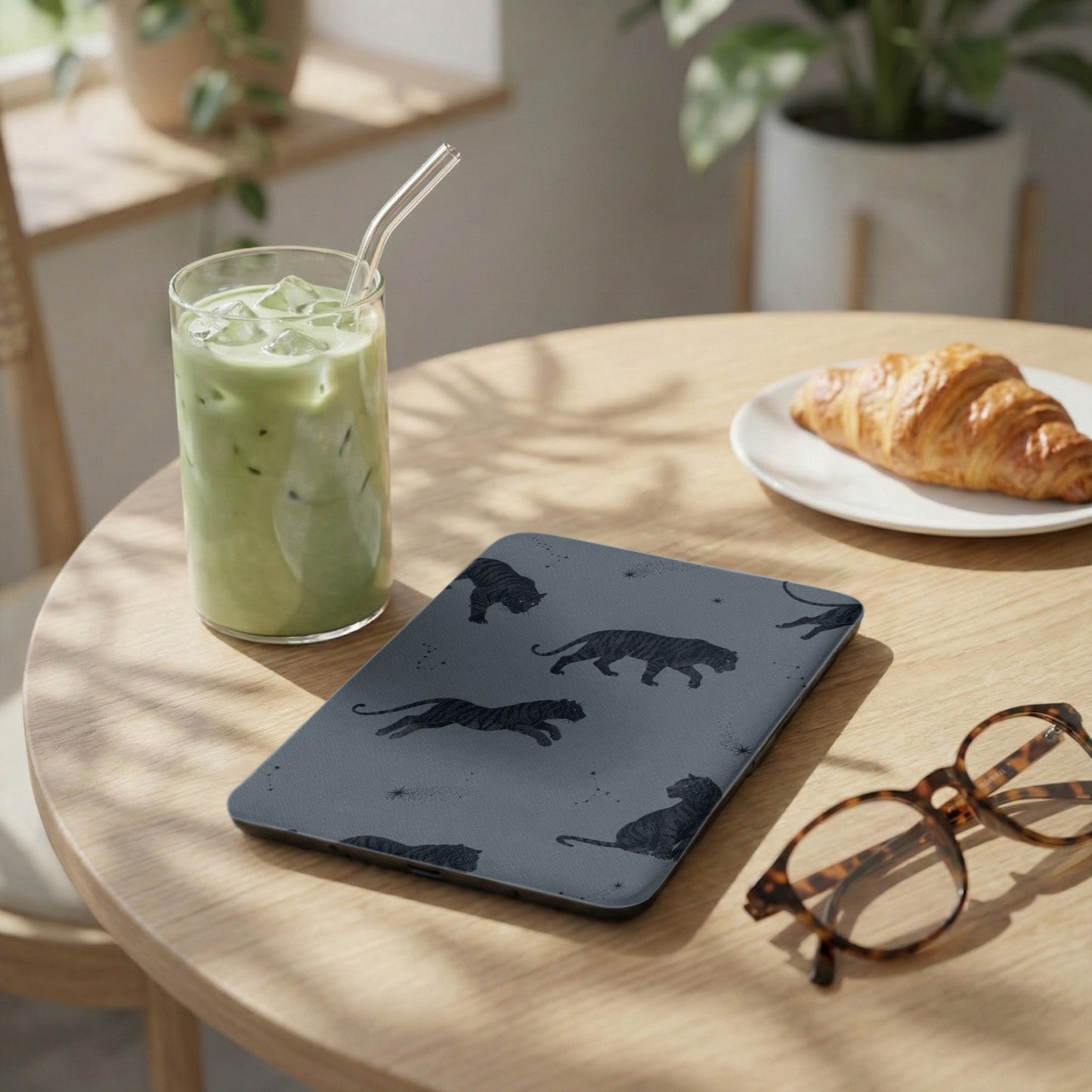 Gray case with black tiger illustrations and stars, next to a glass of green drink.