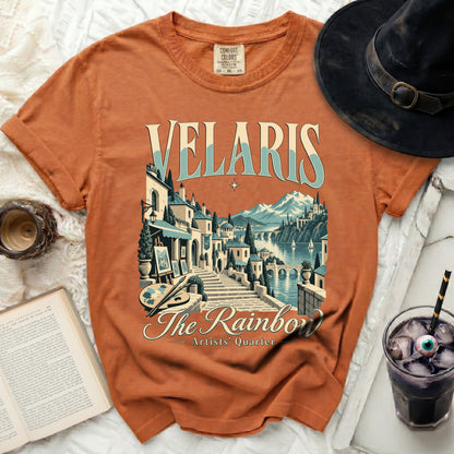 Orange t-shirt with "VELARIS The Rainbow Artists' Quarter" graphic.