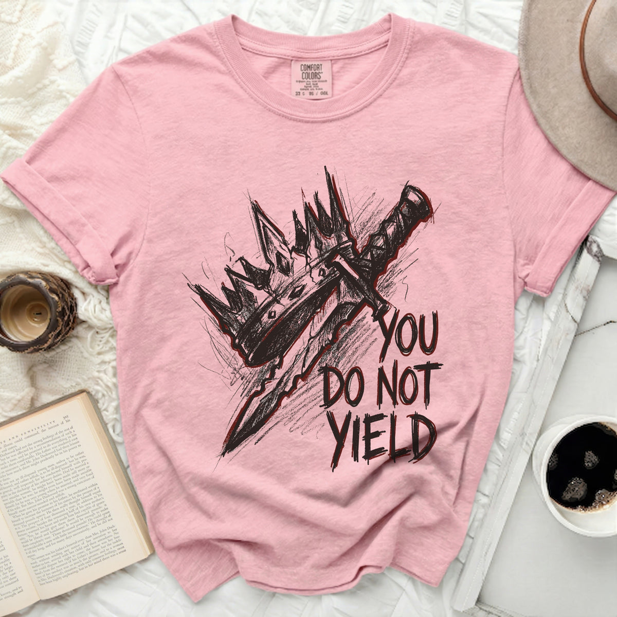 Pink t-shirt with a graphic of a crown and sword, and the text "YOU DO NOT YIELD".