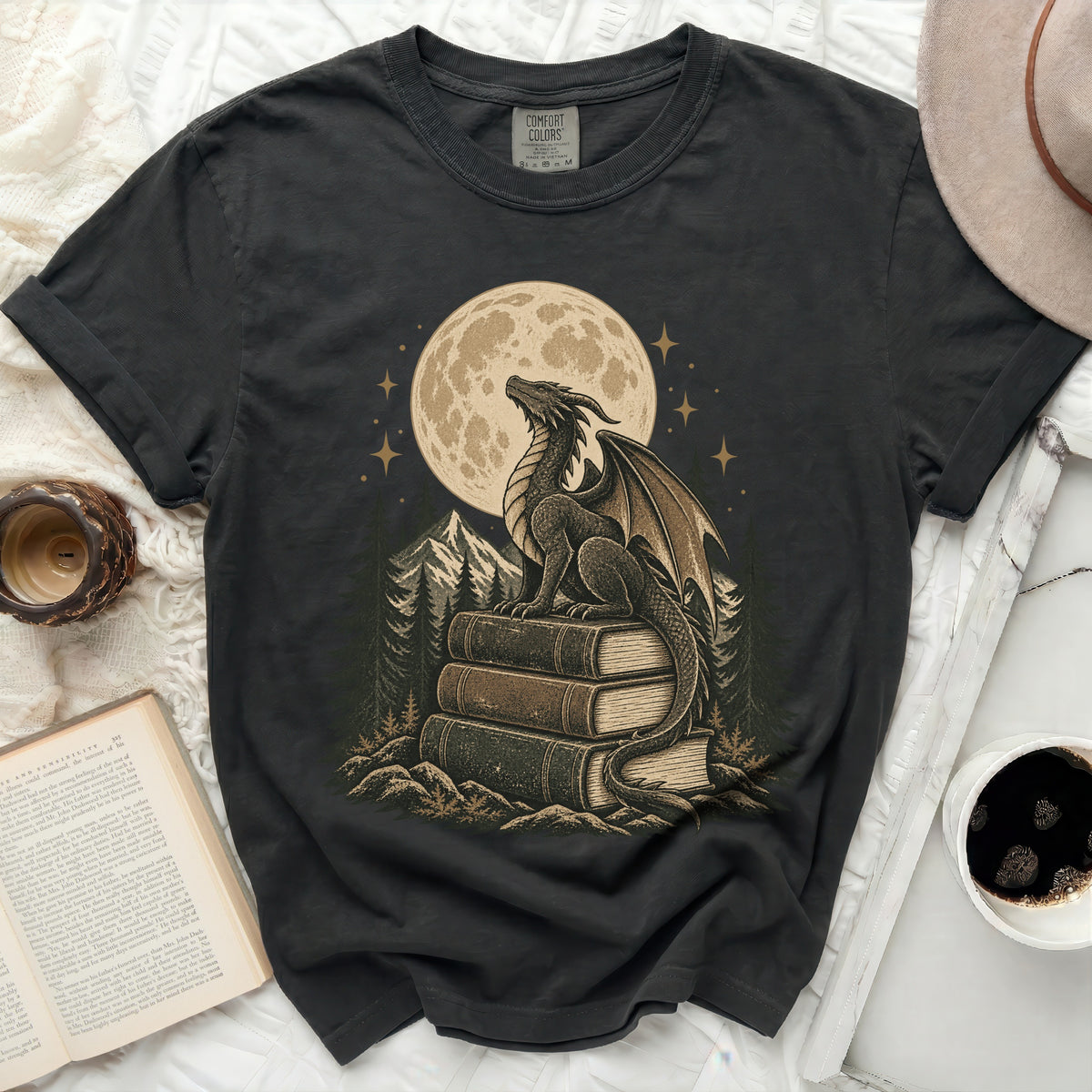 Dark t-shirt with a dragon sitting on books under a full moon.