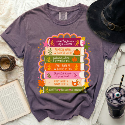 T-shirt with stack of books featuring fall phrases and illustrations.