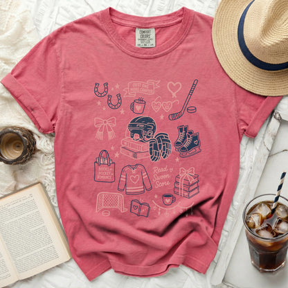 Pink graphic t-shirt with hockey, book, and heart icons and text.