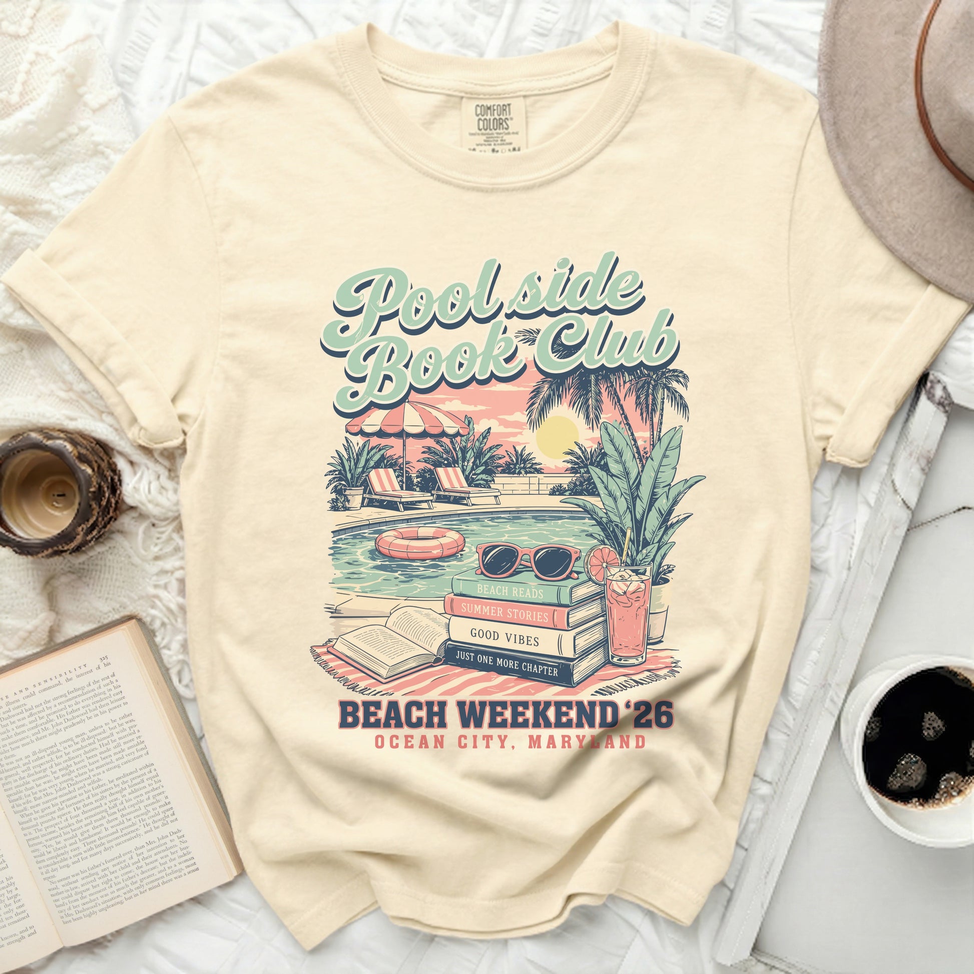 Cream t-shirt with "Poolside Book Club" graphic, beach scene, and text.