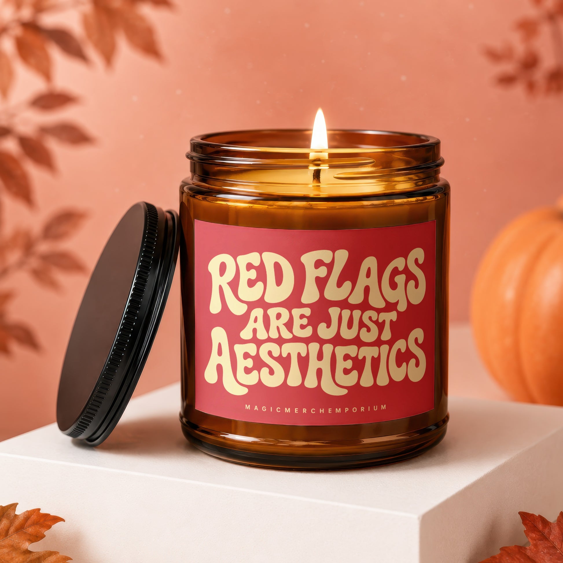 Burning amber candle with red label reading "RED FLAGS ARE JUST AESTHETICS".