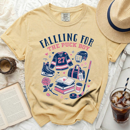 Yellow t-shirt with "Falling For The Puck Boy" graphic and hockey items.